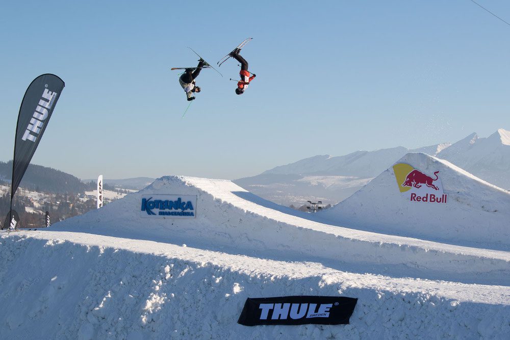Dwóch narciarzy w locie nad skocznią